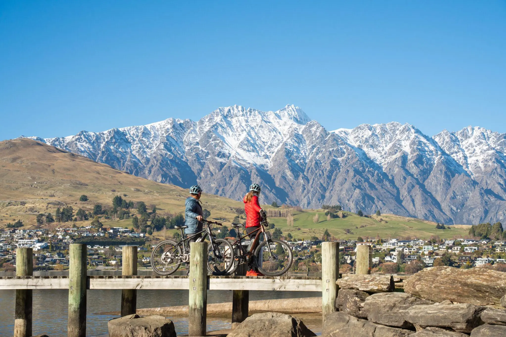 Two Mountain Bike Riders on Wharf looking at Remarkables in Queenstown